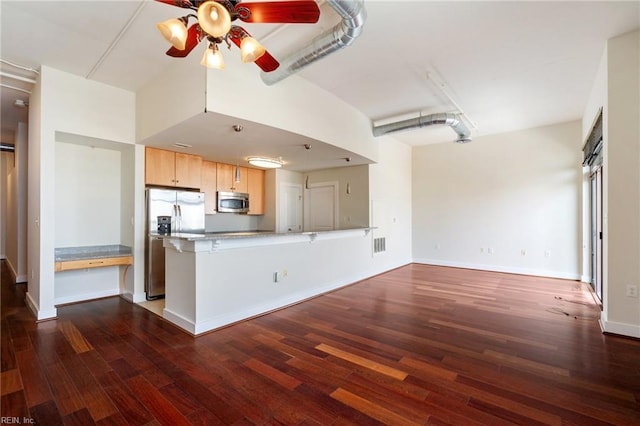 kitchen featuring appliances with stainless steel finishes, dark hardwood / wood-style flooring, light brown cabinetry, and kitchen peninsula