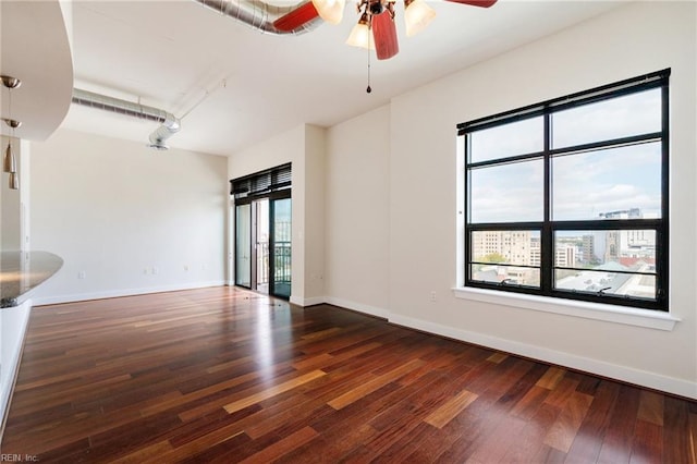 empty room with ceiling fan, dark hardwood / wood-style floors, and a wealth of natural light