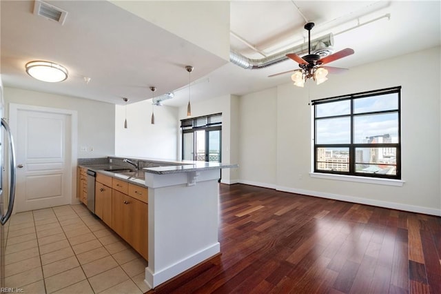 kitchen featuring sink, wood-type flooring, light stone countertops, stainless steel dishwasher, and kitchen peninsula