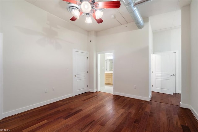 unfurnished bedroom featuring ensuite bath, dark hardwood / wood-style floors, ceiling fan, and a towering ceiling