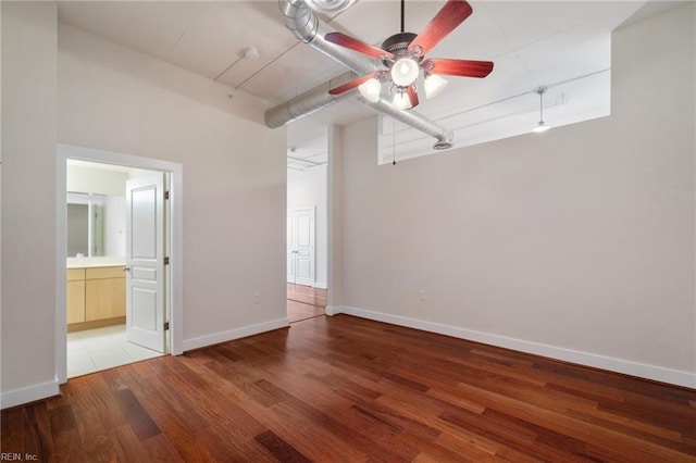 unfurnished bedroom with connected bathroom, hardwood / wood-style floors, and ceiling fan