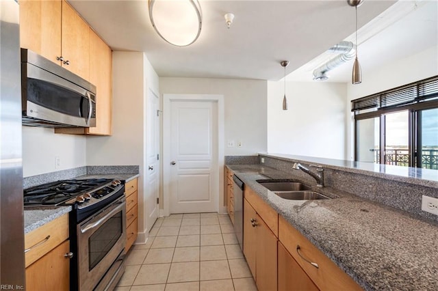 kitchen with decorative light fixtures, sink, dark stone counters, light tile patterned floors, and stainless steel appliances