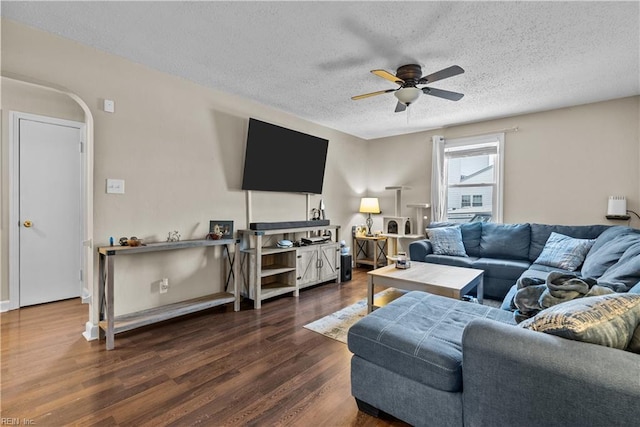 living room featuring ceiling fan, dark hardwood / wood-style floors, and a textured ceiling