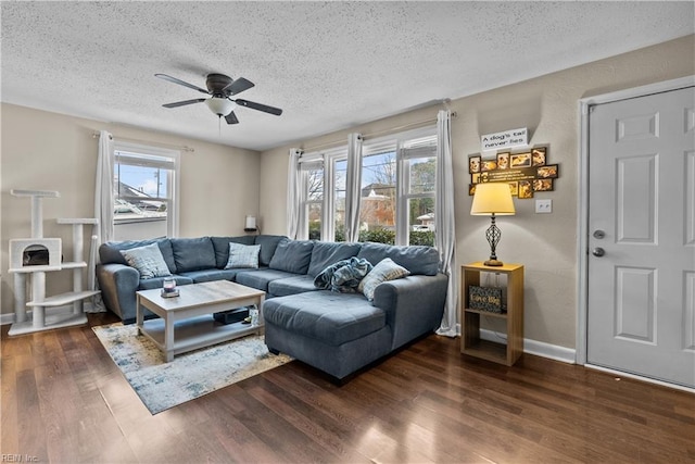 living room with ceiling fan, dark hardwood / wood-style floors, a wealth of natural light, and a textured ceiling