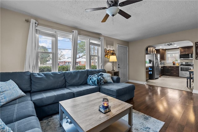 living room featuring ceiling fan, light hardwood / wood-style floors, and a textured ceiling