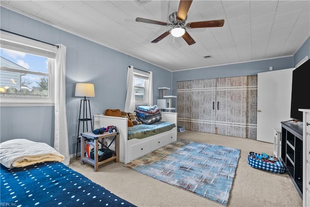 carpeted bedroom featuring multiple windows, crown molding, and ceiling fan