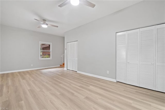 unfurnished bedroom featuring ceiling fan, two closets, and light hardwood / wood-style flooring