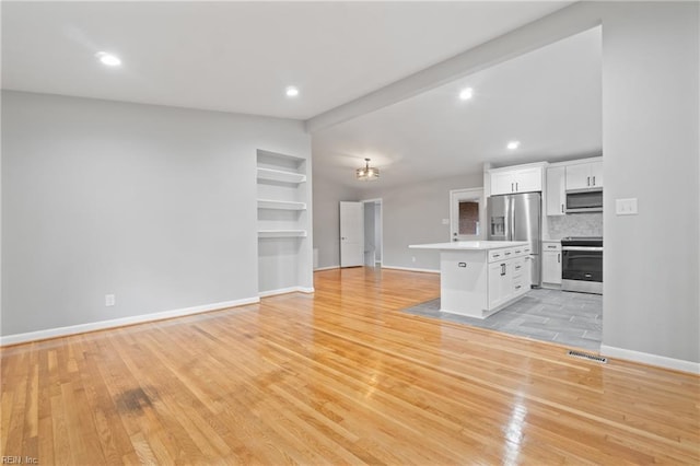 kitchen featuring light hardwood / wood-style floors, tasteful backsplash, white cabinetry, stainless steel appliances, and lofted ceiling with beams