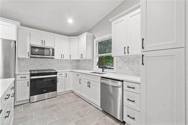 kitchen featuring decorative backsplash, sink, white cabinetry, and appliances with stainless steel finishes