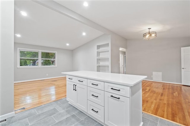 kitchen with a center island, white cabinetry, and lofted ceiling