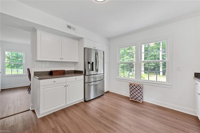 kitchen with stainless steel refrigerator with ice dispenser, light hardwood / wood-style floors, white cabinetry, and dark stone countertops