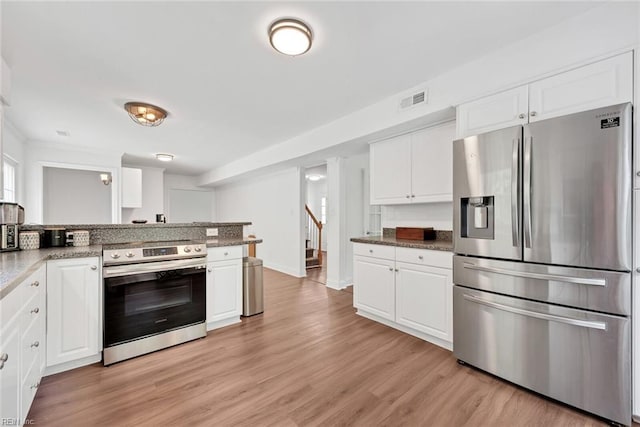 kitchen with stainless steel appliances, white cabinetry, and stone countertops