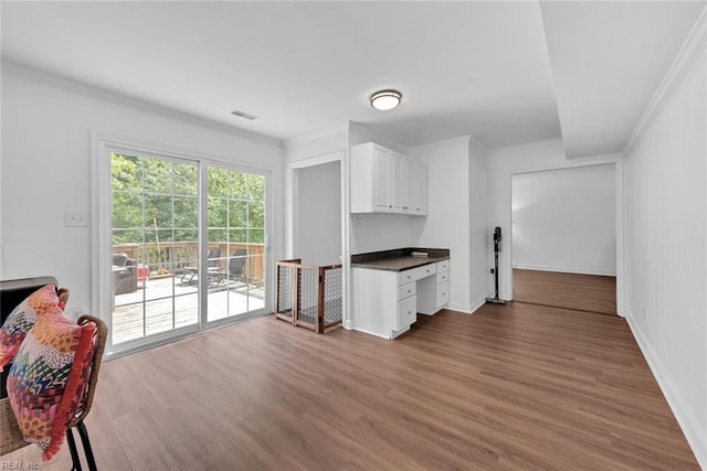 kitchen featuring ornamental molding, white cabinets, dark wood-type flooring, and built in desk