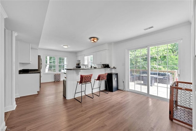 kitchen featuring kitchen peninsula, white cabinets, a wealth of natural light, and dark hardwood / wood-style flooring