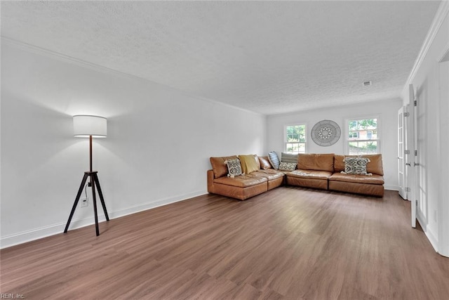 unfurnished living room featuring hardwood / wood-style flooring, a textured ceiling, and ornamental molding