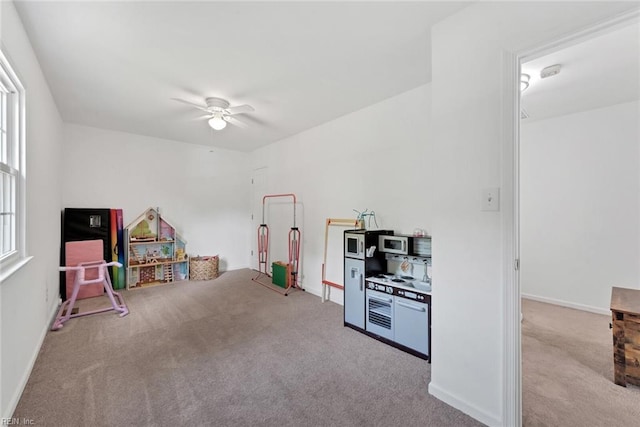 game room with ceiling fan, a wealth of natural light, and light carpet