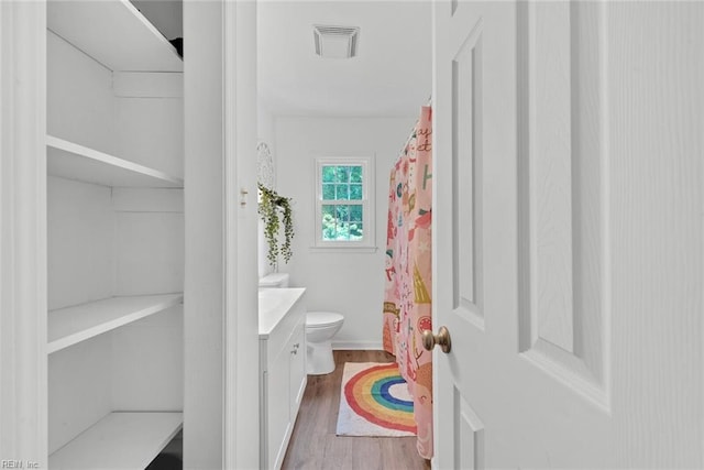 bathroom with vanity, toilet, walk in shower, and wood-type flooring