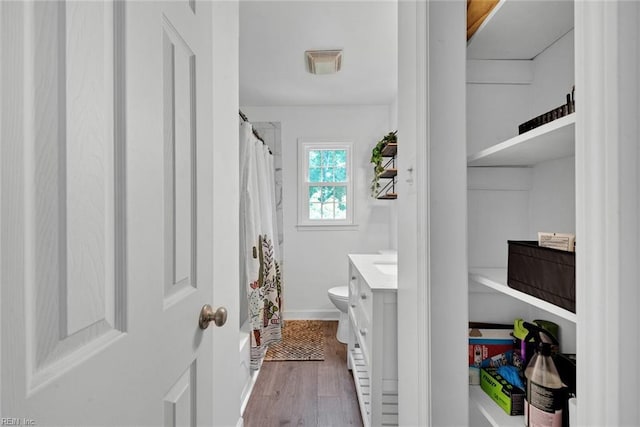 bathroom with hardwood / wood-style floors, toilet, vanity, and walk in shower