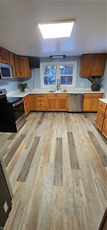 kitchen featuring appliances with stainless steel finishes, sink, and light hardwood / wood-style floors