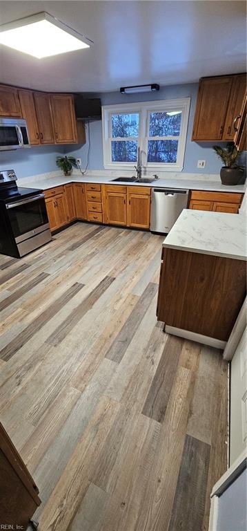 kitchen featuring stainless steel appliances, sink, and light wood-type flooring