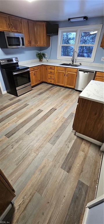 kitchen featuring appliances with stainless steel finishes, sink, and light wood-type flooring