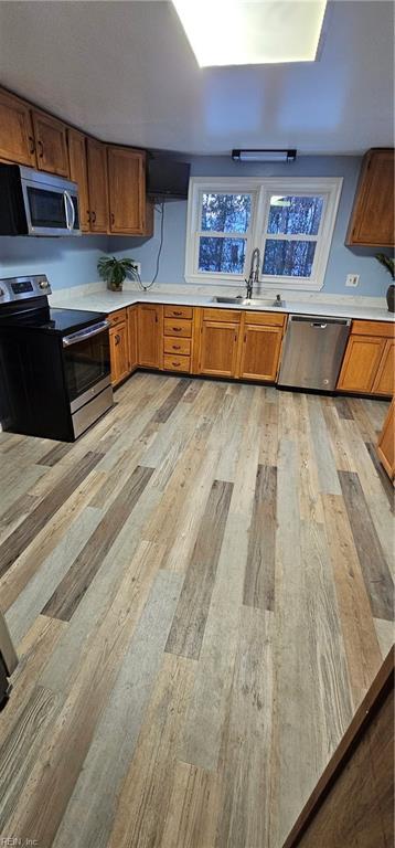 kitchen with sink, stainless steel appliances, and light hardwood / wood-style floors