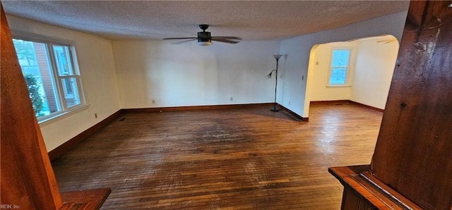 unfurnished room with a textured ceiling, dark wood-type flooring, and ceiling fan