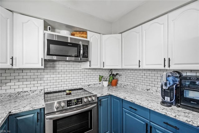 kitchen with blue cabinetry, decorative backsplash, white cabinetry, and appliances with stainless steel finishes