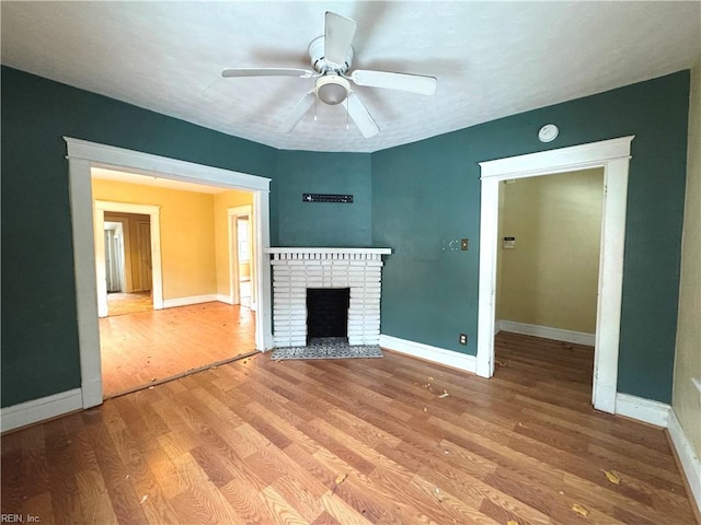 unfurnished living room with ceiling fan, a textured ceiling, a fireplace, and wood-type flooring