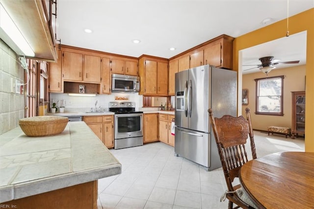 kitchen featuring ceiling fan, appliances with stainless steel finishes, sink, and backsplash