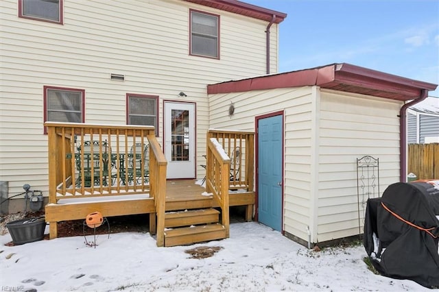 snow covered rear of property with a deck