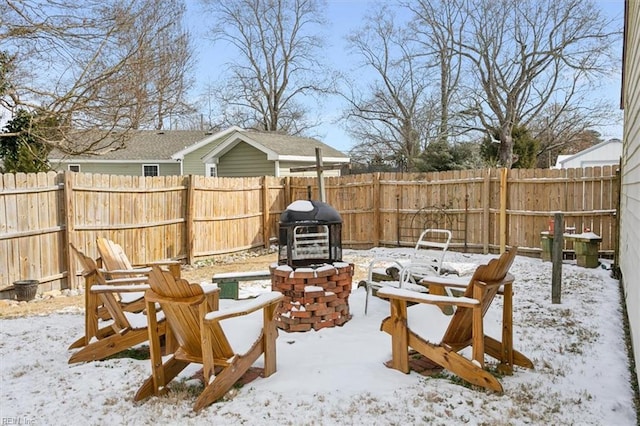 snow covered patio featuring grilling area and an outdoor fire pit