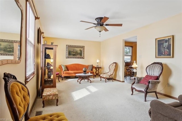 living area featuring light colored carpet and ceiling fan