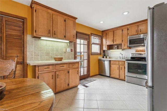 kitchen featuring light tile patterned floors, appliances with stainless steel finishes, sink, and backsplash