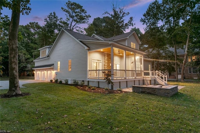 property exterior at dusk with a garage, covered porch, and a lawn