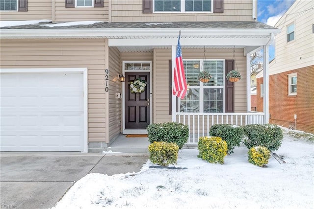 snow covered property entrance with a garage and a porch