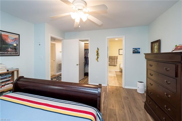 bedroom featuring ensuite bath, a spacious closet, light hardwood / wood-style flooring, a closet, and ceiling fan