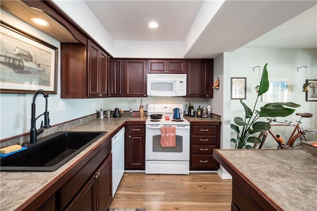 kitchen with white appliances, tile counters, sink, and light wood-type flooring