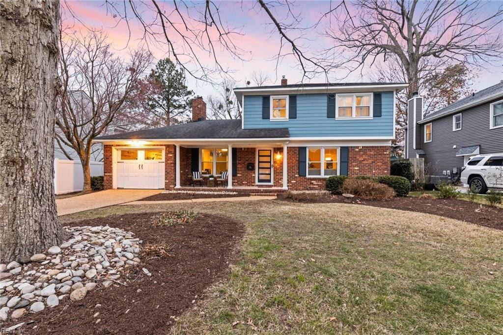 view of front property with a garage, covered porch, and a lawn