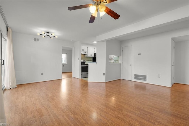 unfurnished living room featuring ceiling fan with notable chandelier and light hardwood / wood-style floors