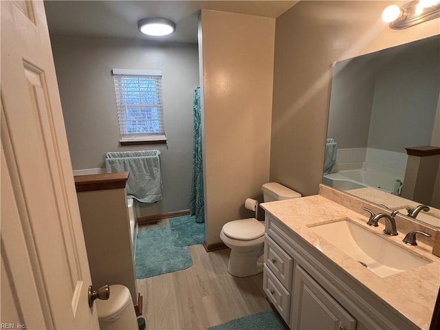 bathroom featuring wood-type flooring, a washtub, vanity, and toilet