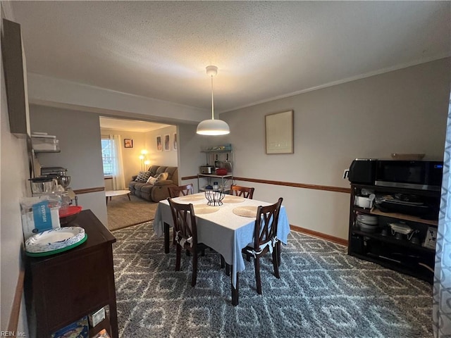 carpeted dining room featuring a textured ceiling