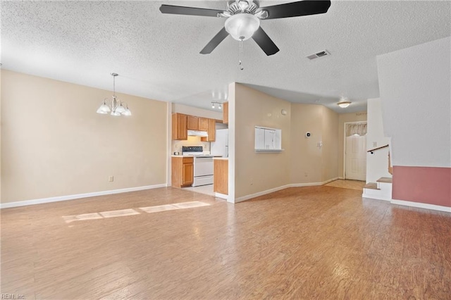 unfurnished living room featuring ceiling fan with notable chandelier, a textured ceiling, and light wood-type flooring