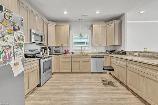 kitchen featuring sink, stainless steel appliances, light hardwood / wood-style floors, decorative light fixtures, and light brown cabinets