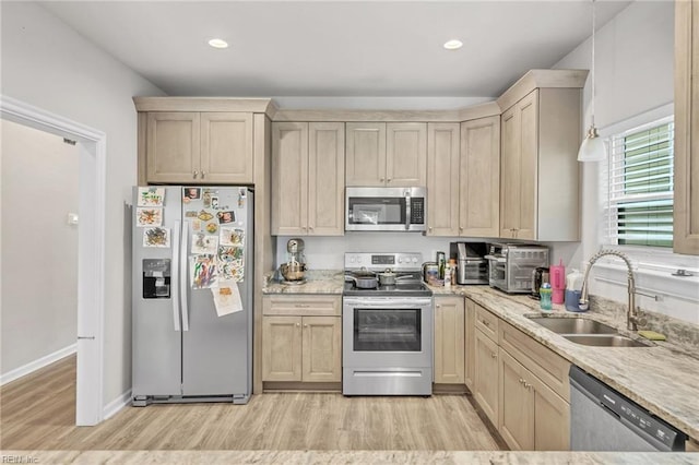 kitchen with appliances with stainless steel finishes, sink, light brown cabinets, and light wood-type flooring