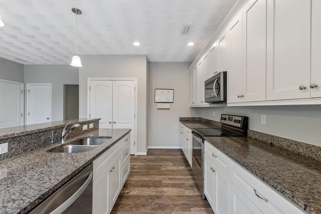 kitchen with pendant lighting, white cabinetry, sink, dark stone counters, and stainless steel appliances