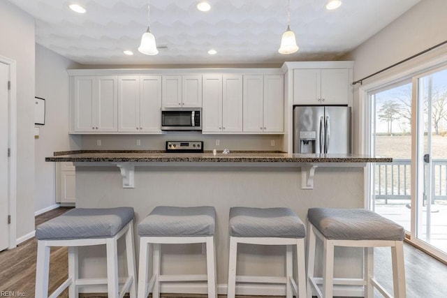 kitchen featuring white cabinetry, appliances with stainless steel finishes, a center island, and a kitchen breakfast bar