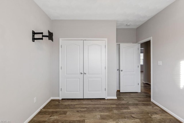 unfurnished bedroom with dark hardwood / wood-style flooring and a closet