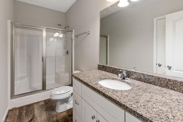 bathroom with vanity, hardwood / wood-style floors, an enclosed shower, and toilet