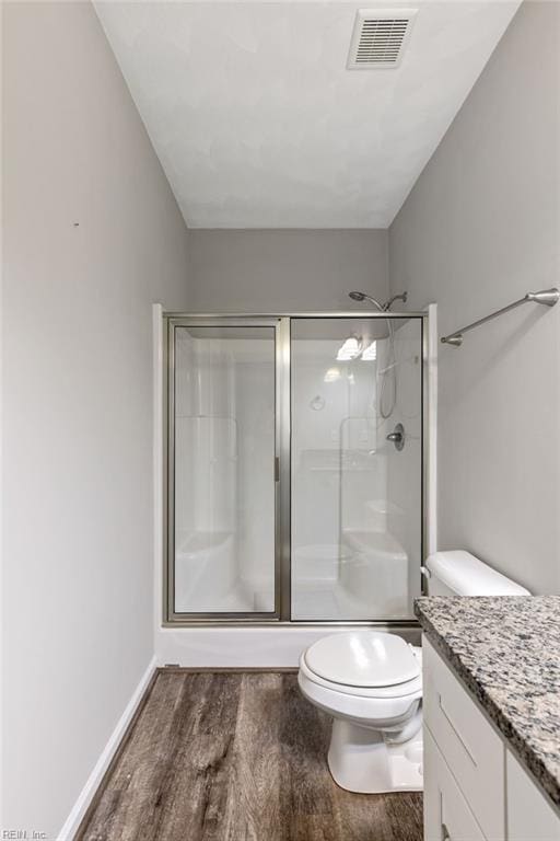 bathroom featuring walk in shower, vanity, toilet, and hardwood / wood-style floors